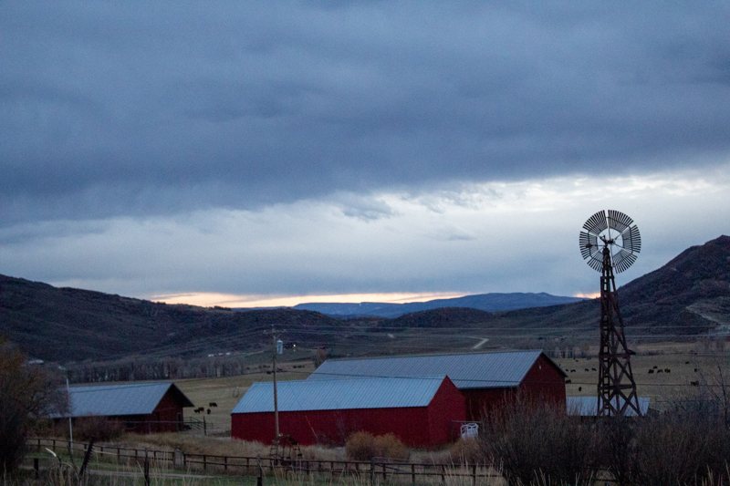 Red farm buildings and a windmill under moody sky