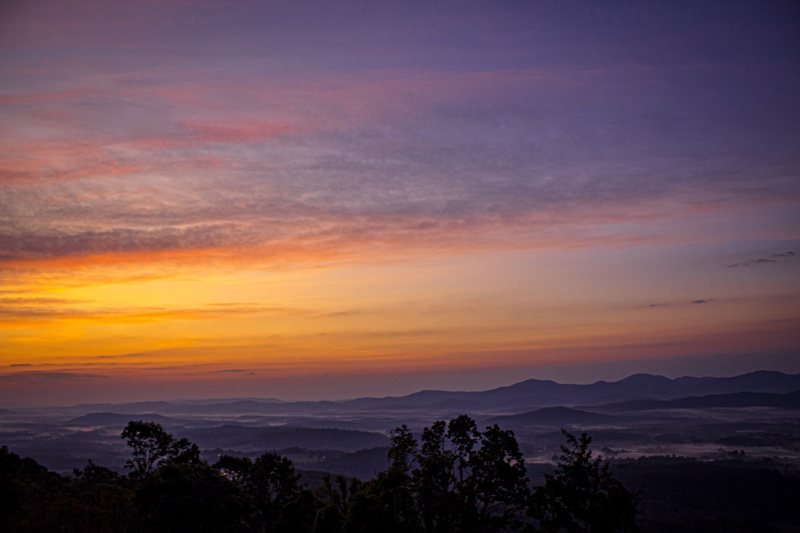 Purple and orange sunrise over misty layered mountains
