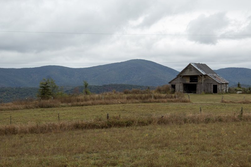 Weathered barn in a field below mountains