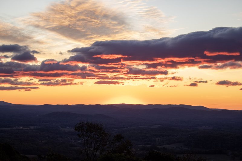 Orange band of sunset beneath heavy dark clouds