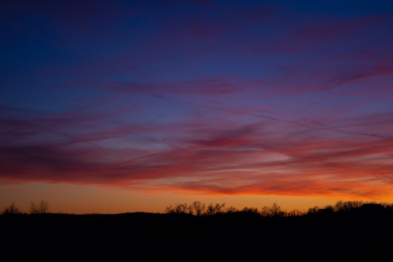 Red and magenta sunset over a dark horizon