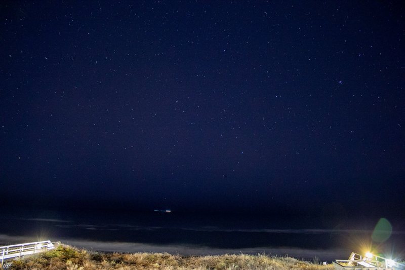 Deep blue night sky over a shoreline with faint lights