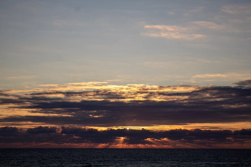 Sunset over a lake beneath layered clouds