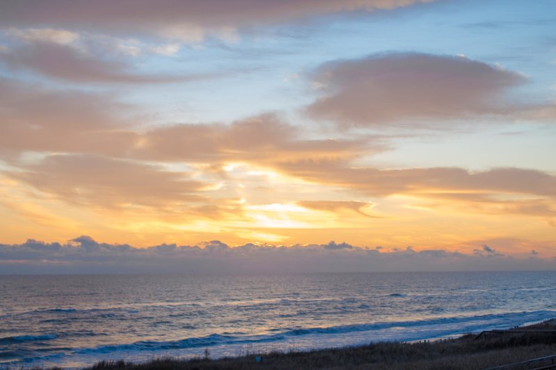 Golden sunrise over the ocean with waves and dune grass